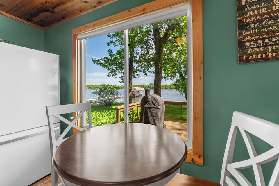 Picture yourself at this cozy dining nook with serene lake views just beyond your door. The soft green walls and rustic wood accents create a warm retreat where morning coffee tastes even better.