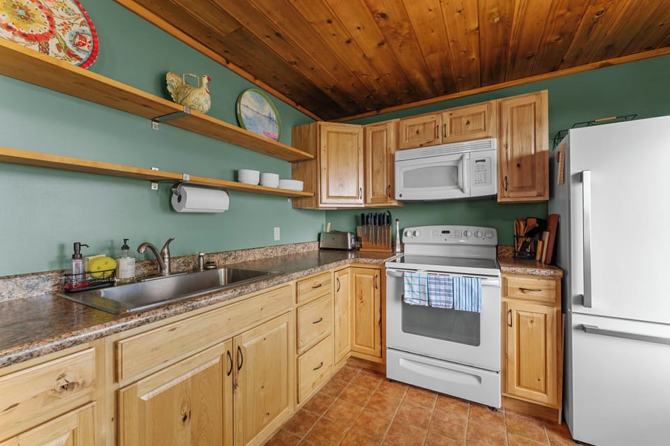 Cook your favorite meals in this fully-equipped kitchen featuring warm wood cabinetry, granite countertops, and all the modern appliances you need to feel right at home.