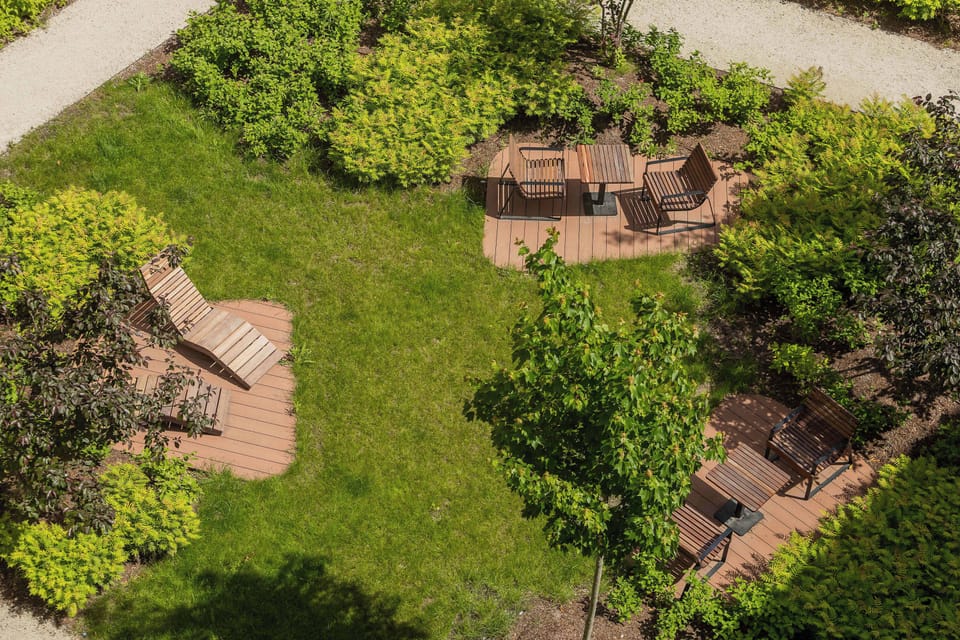 A landscaped courtyard with green lawns, trees, and outdoor seating areas. The space provides a pleasant place to relax outdoors.