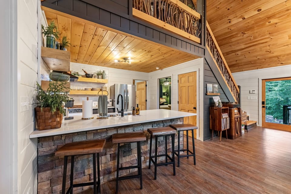 Plants, thoughtful touches, cozy stools, and rich textures bring warmth and personality into this beautifully designed open-concept kitchen.