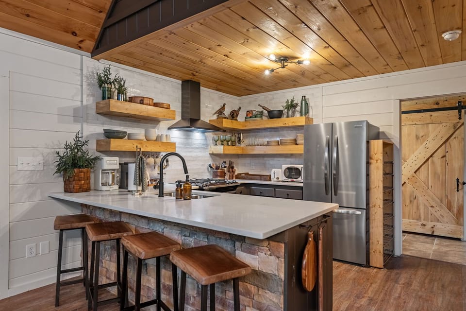 White-painted wood walls and warm natural textures give the kitchen its signature blend of rustic mountain charm and elevated modern comfort.