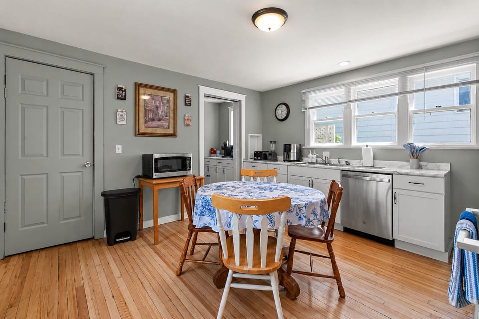 Bright eat-in kitchen with sunny windows, wood floors, and cozy dining table