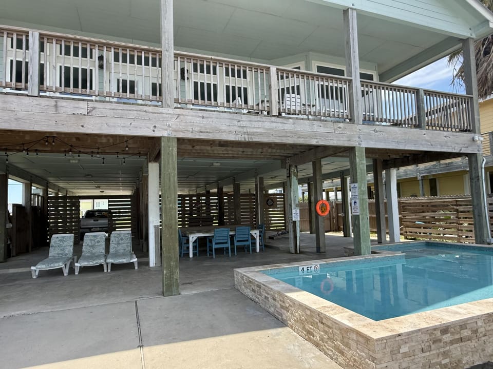 Covered patio and pool beneath a raised deck.