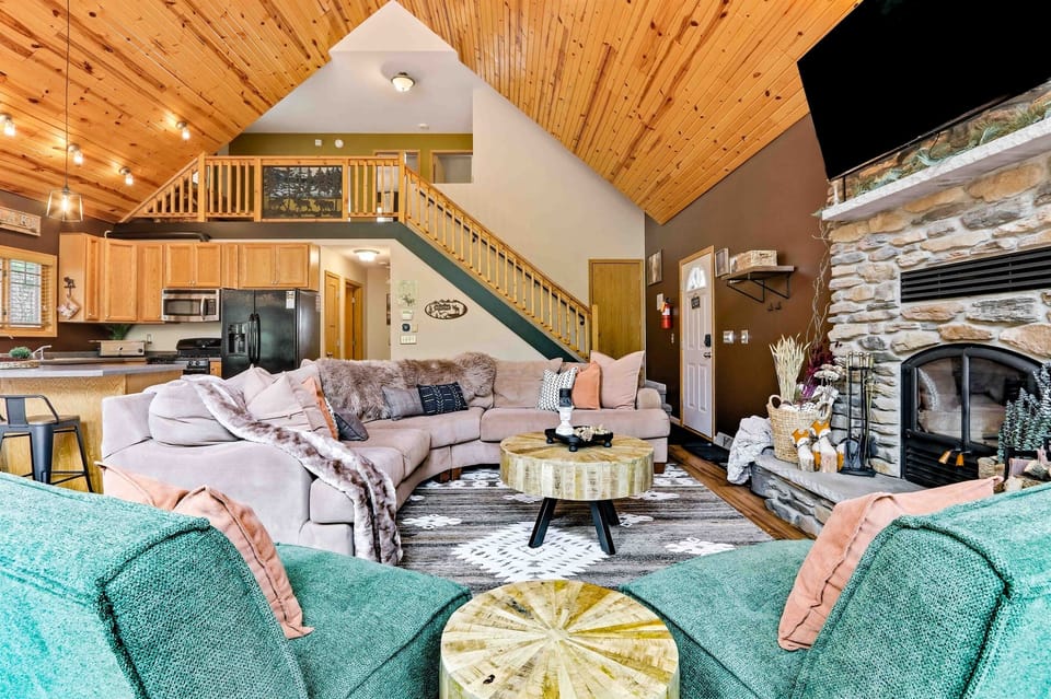 Spacious cabin-style great room with cozy seating, soaring ceilings, and an inviting fireplace centerpiece.