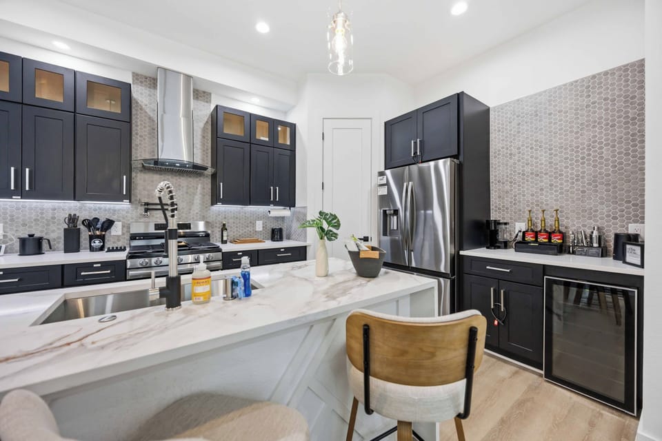 Stocked, gourmet kitchen with island seating, wine fridge, and sleek finishes