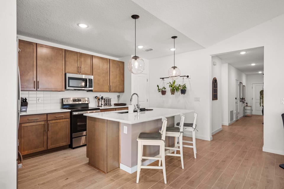 Modern kitchen with island seating, stainless appliances & tile backsplash