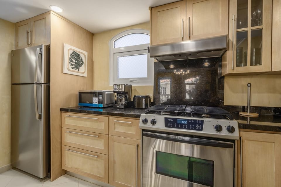 Fully equipped kitchen with modern appliances, drip coffee maker, microwave, fridge, and gas stove range.