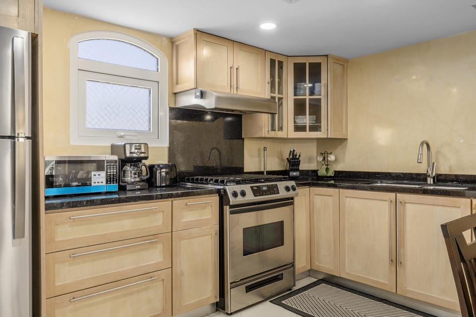 Fully equipped kitchen with modern appliances, drip coffee maker, microwave, and gas stove range.