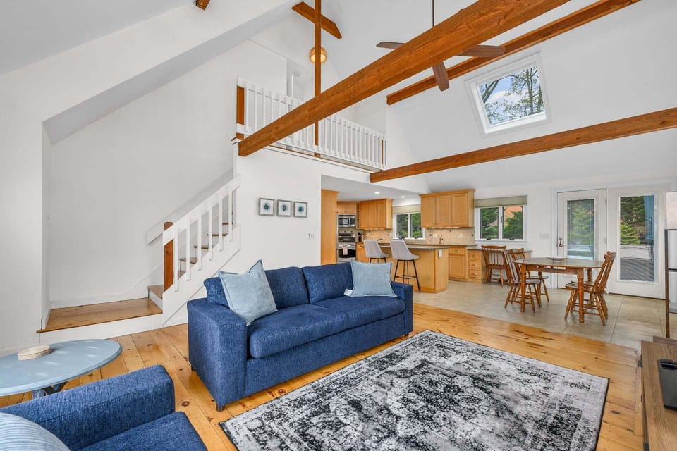 Cathedral ceilings with exposed beams overlooking the living room, dining area, and kitchen