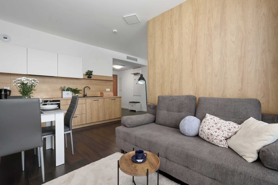 A view of the open living room space with a sofa and kitchen cabinets in the background. Warm lighting gives the room a homey and peaceful atmosphere.