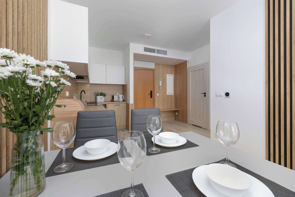 A dining table set for two, adorned with elegant tableware. In the background, a vase with a large bouquet of white flowers adds a touch of freshness to the interior.