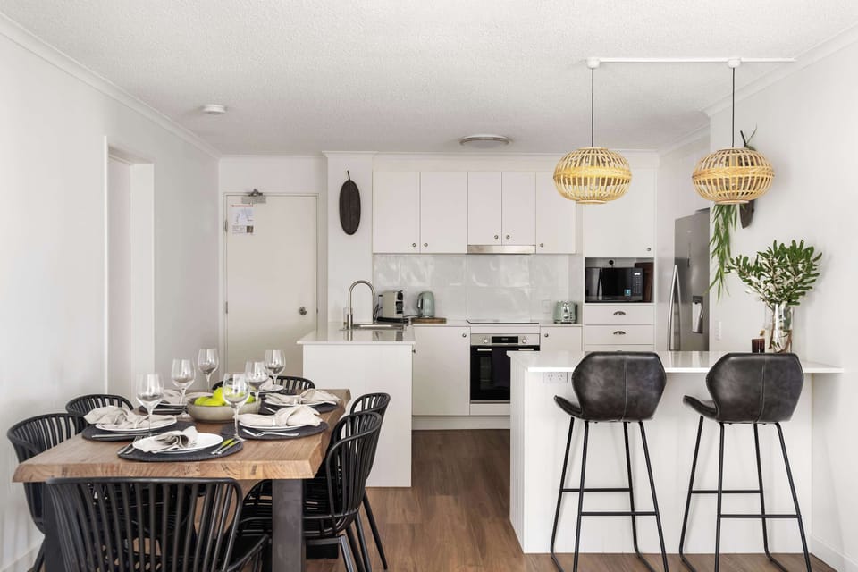 A spacious dining area flows seamlessly into the kitchen, creating a warm, inviting space to gather after a day at the beach.