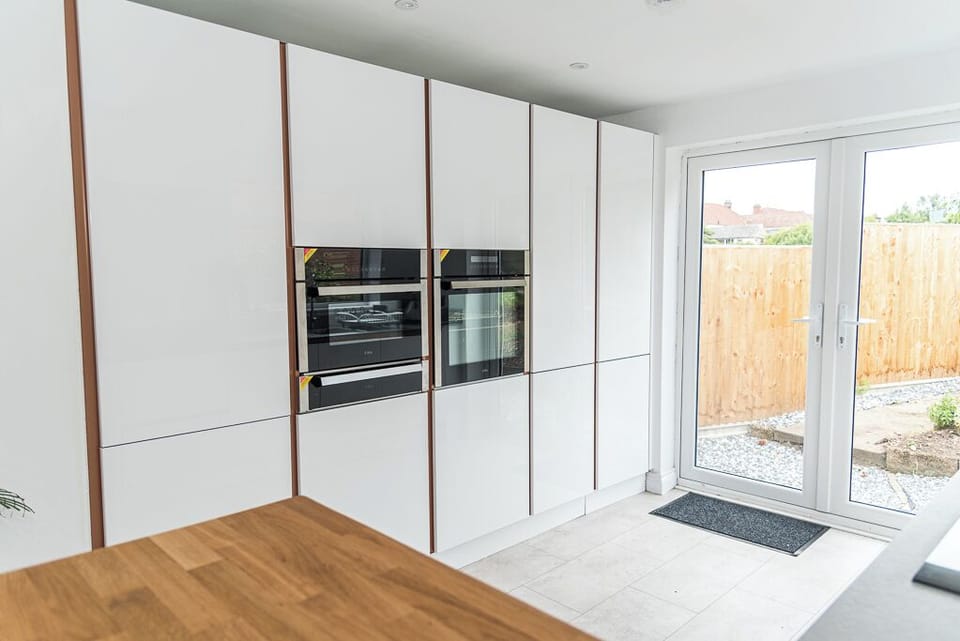 The kitchen features sleek floor-to-ceiling cabinetry with integrated double ovens, clean, modern, and well-equipped for cooking in style.
