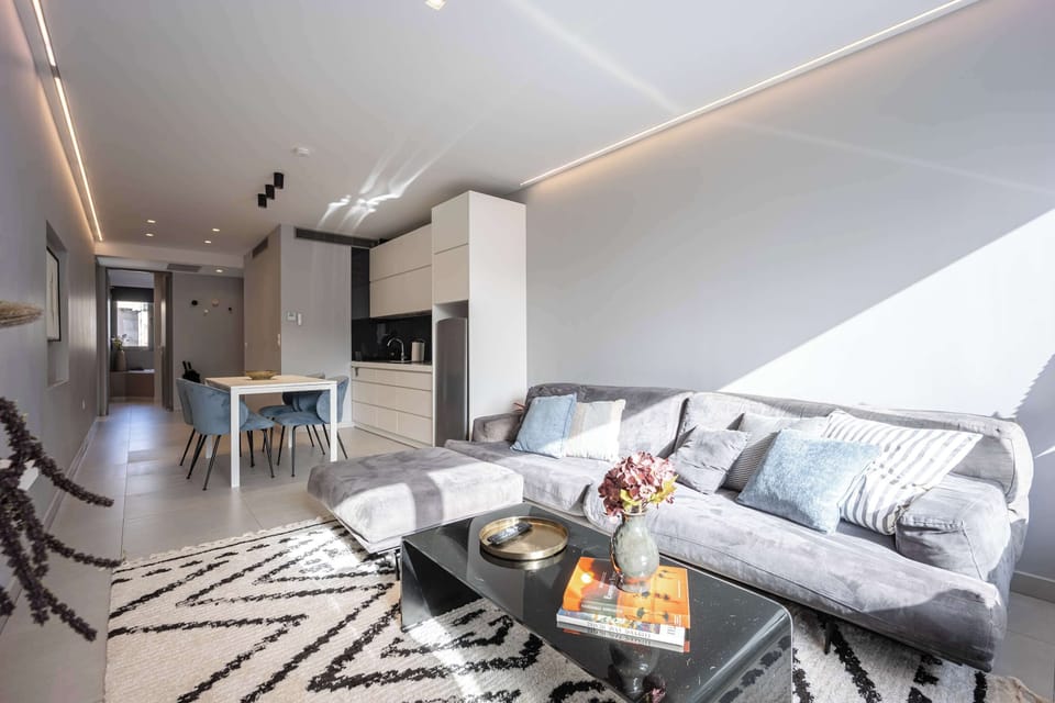 Sun-drenched living space showcases plush seating and airy layout, offering relaxing moments with bright city energy.