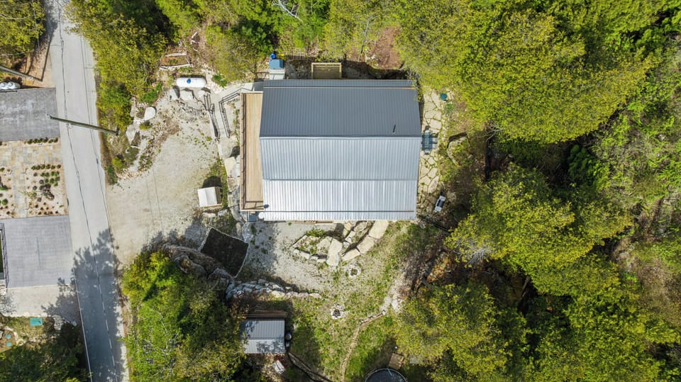 Hidden in plain sight. Clear metal roof, stone patios, and completely enveloped by the green canopy.