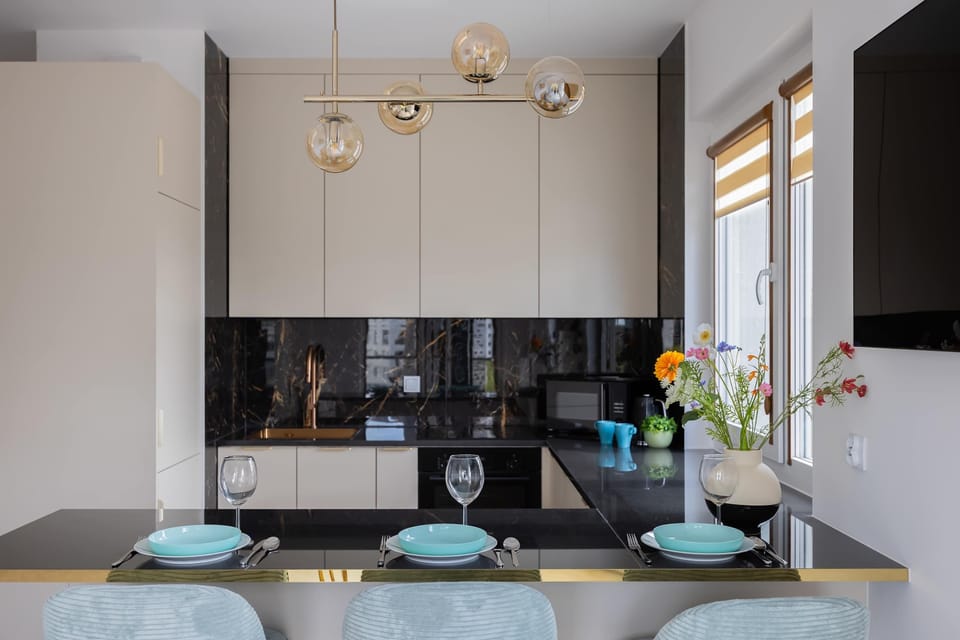 A frontal view of the breakfast bar shows three elegant blue stools lined up neatly. A decorative vase with delicate flowers sits on the counter, adding a touch of nature to the modern interior.