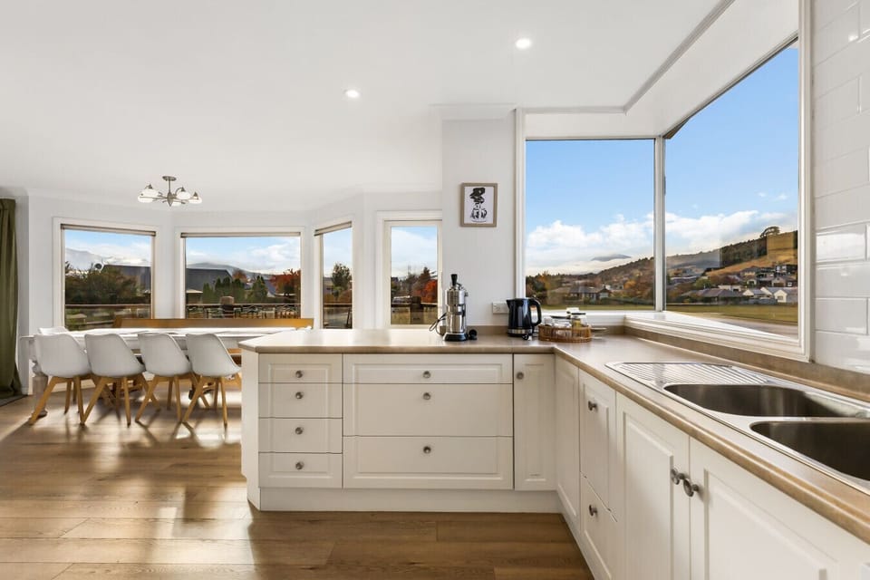 Modern white kitchen with island bench and spectacular hillside outlook