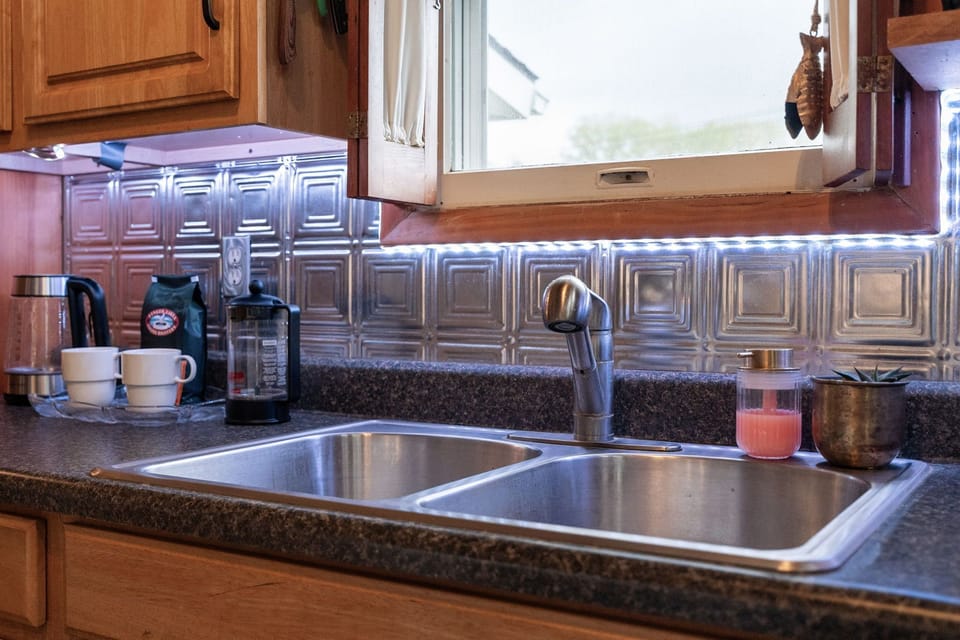 Bright kitchen sink overlooking the trees, with soft lighting throughout the space.