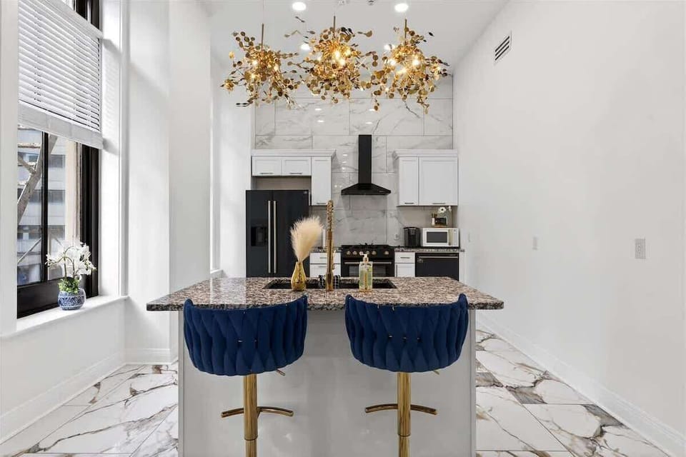 The kitchen features a spectacular gold Sputnik chandelier above the granite island. Pull up a blue velvet bar stool and enjoy the luxe vibe.