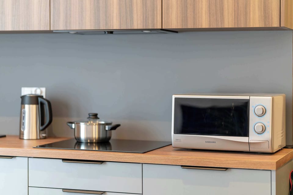 A kitchen countertop with small appliances such as a microwave and kettle. The space is practical and ideal for quick meal preparation.