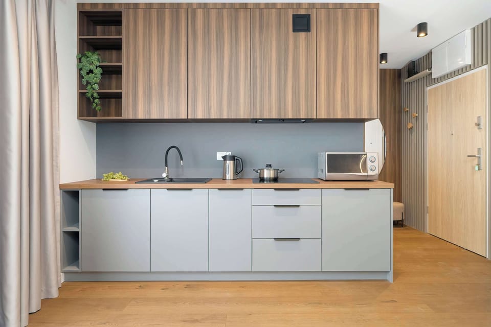 A modern kitchen area with sleek cabinets and integrated appliances. The design is functional and clean, offering everything needed for cooking.