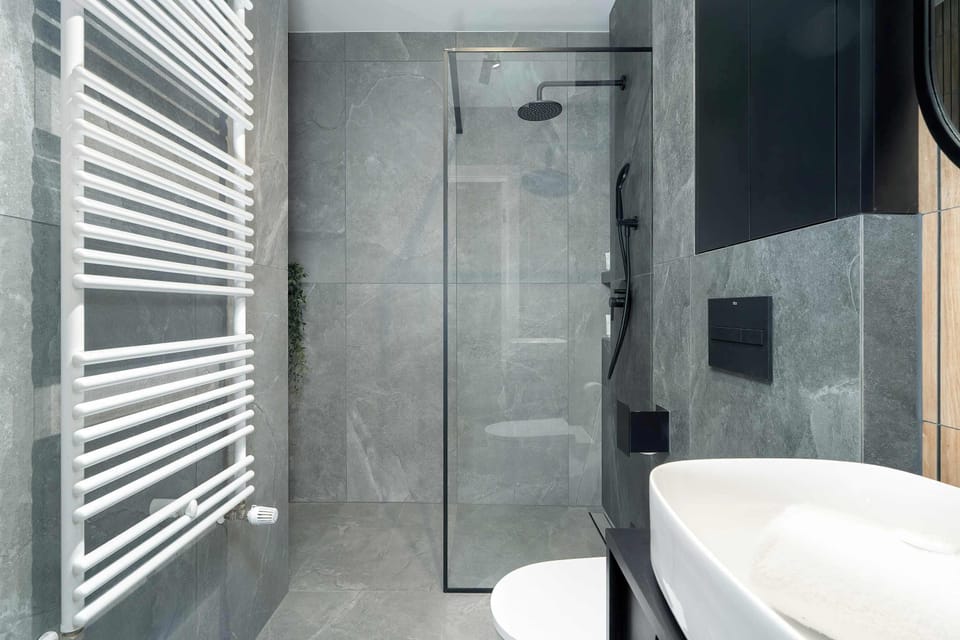 Another angle of the bathroom showing the shower area and towel radiator. The space is practical, modern, and well-maintained.