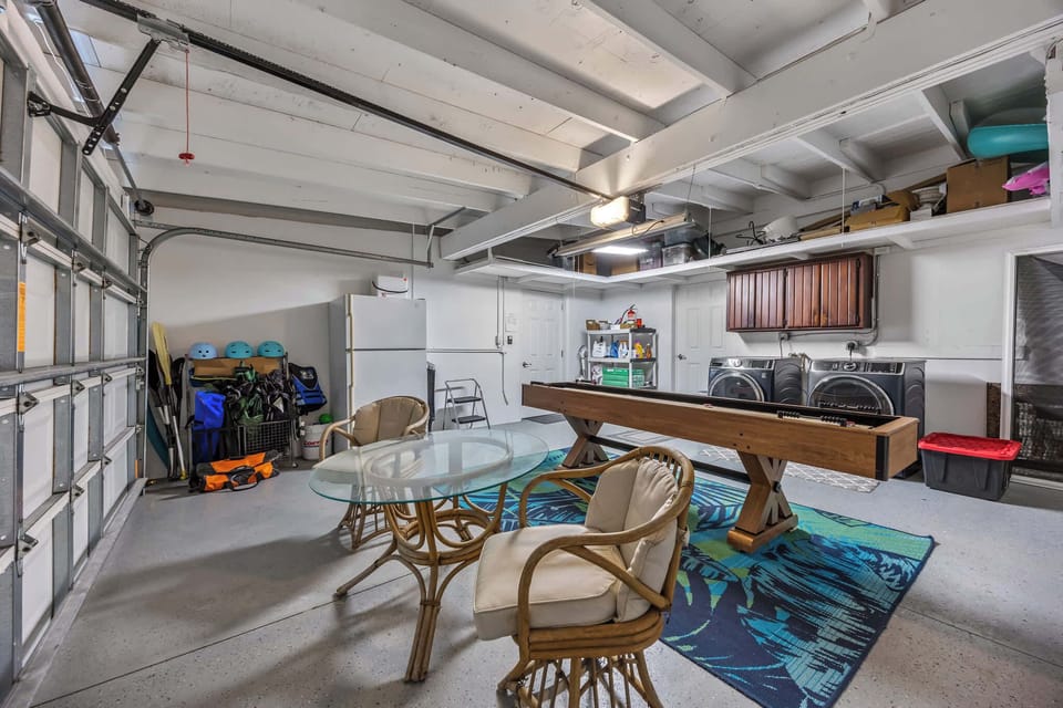 Recreation room with shuffleboard table, seating area, and laundry appliances.