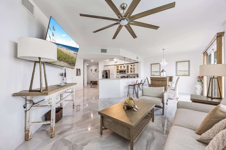 Open-concept living area with modern coastal decor and a large ceiling fan.