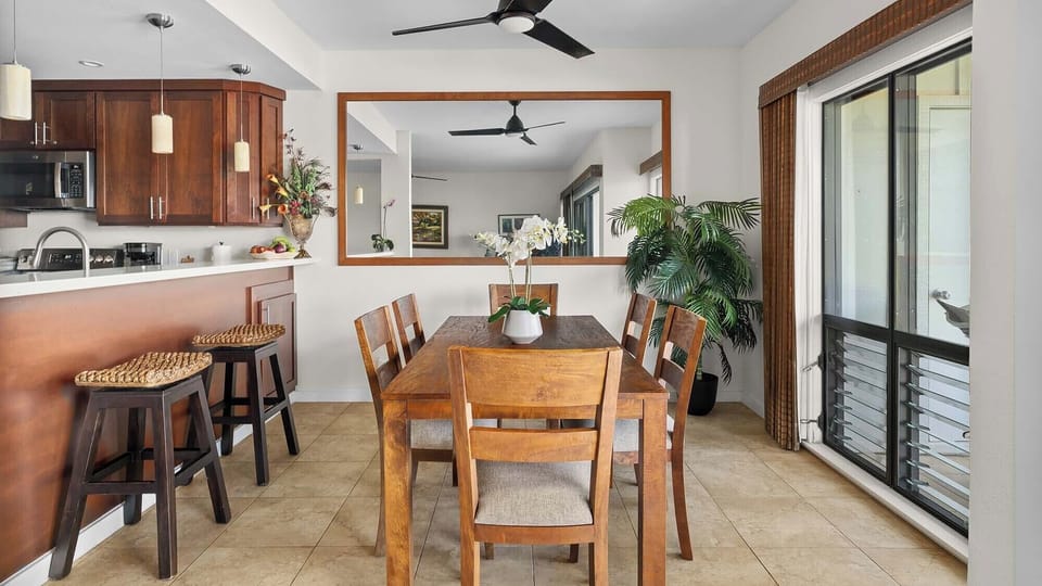 Gather around this inviting dining table for meals and conversation, with a fully equipped kitchen just steps away and tropical breezes flowing through open doors to your private outdoor space.