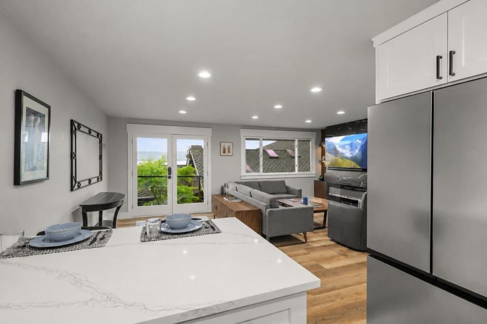 Bright open-concept kitchen and living space featuring modern finishes, stainless steel appliances, and easy access to the private balcony with partial lake views.