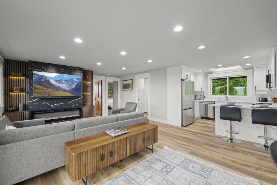 Modern open-concept living area featuring a comfortable sofa, Smart TV, and a fully equipped kitchen with bar seating, perfect for gathering with family and friends.