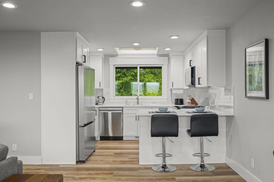 Bright and fully renovated kitchen equipped with modern appliances, spacious countertops, and bar seating for casual dining.