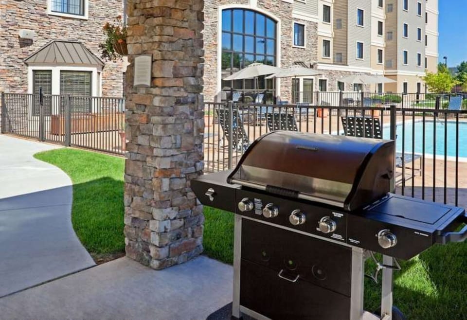 Outdoor pool area with barbecue grills and lounge seating.