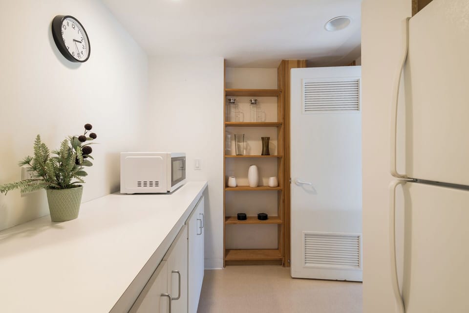 Your kitchen offers a clean, functional space with modern appliances, open shelving for your pantry essentials, and a microwave ready for quick meals during your stay.