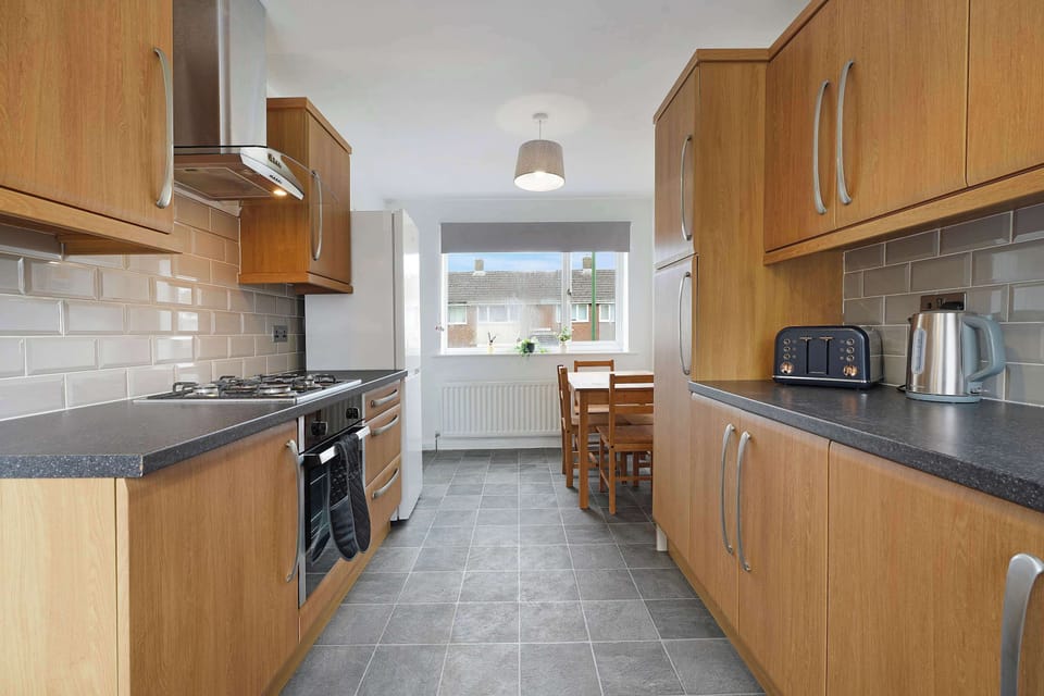 This thoughtfully equipped kitchen combines practicality and convenience with a full-size dishwasher, oven, hob, fridge-freezer, cookware, and easy access to the outdoor area.