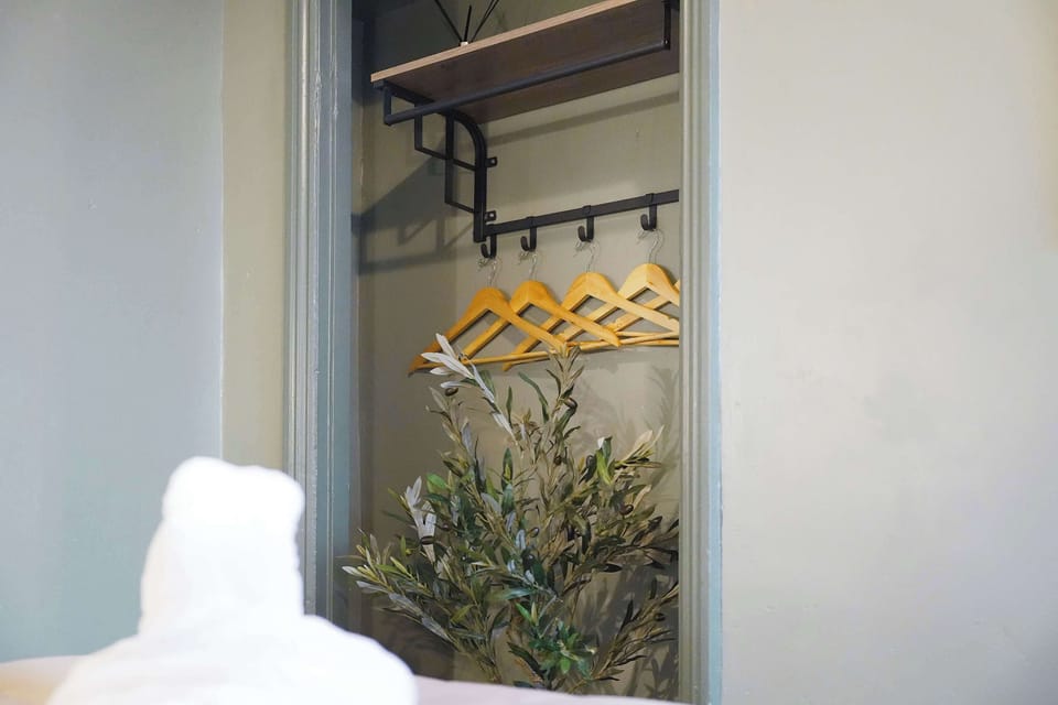 A welcoming bedroom featuring useful hanging storage, a mirror, and practical details for a convenient stay. The simple arrangement adds functionality while complementing the comfortable and relaxing bedroom space.