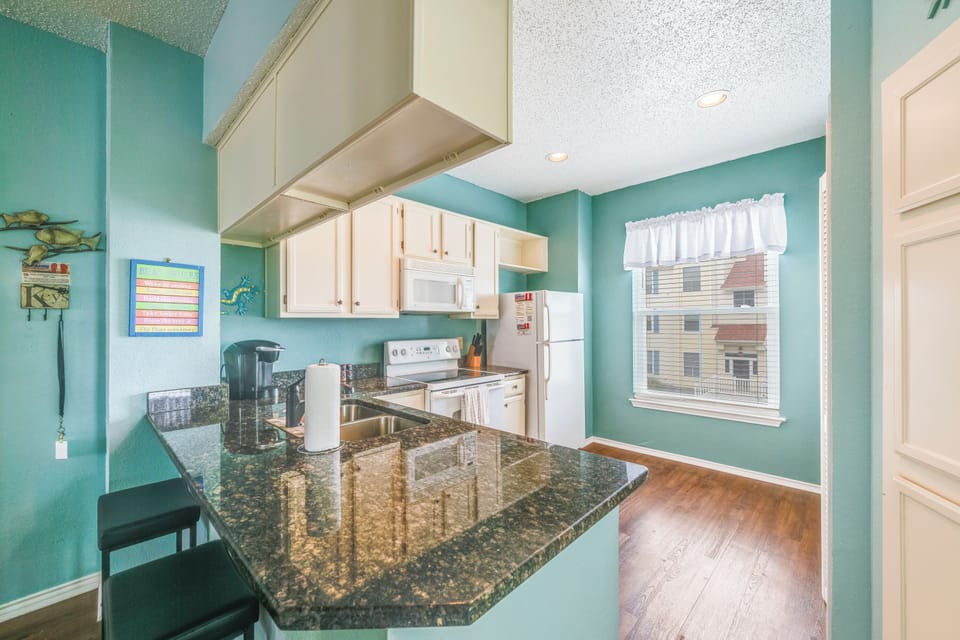 Bright, fully equipped kitchen with granite countertops, modern appliances, and an open layout that makes preparing meals easy and enjoyable.
