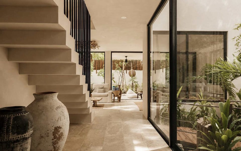 A serene entryway with a sculptural staircase, floor-to-ceiling glass, and lush indoor gardens that immediately set the tone for Tulumaya’s natural, open-air design.