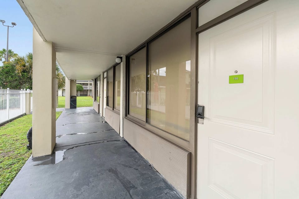 Covered walkway leading to the entrance of unit 186 with large windows overlooking the green lawn.