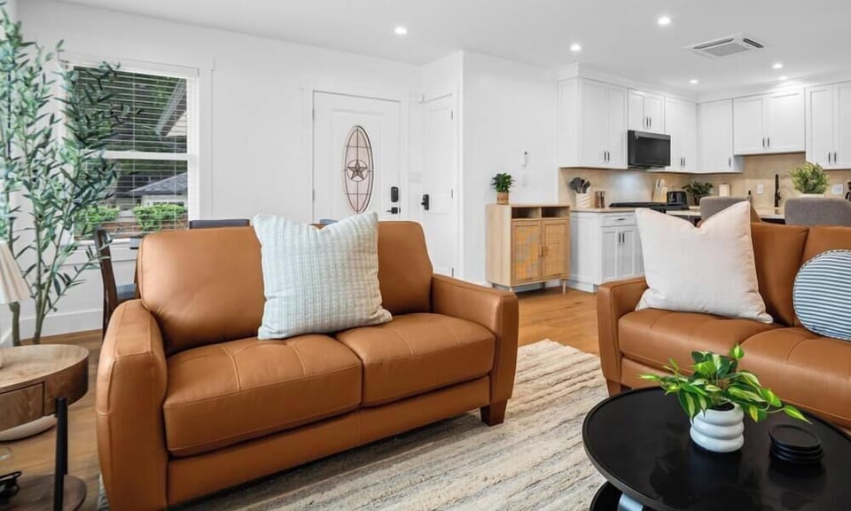 Bright living room with comfortable leather seating, a stylish coffee table, and an open view into the kitchen.