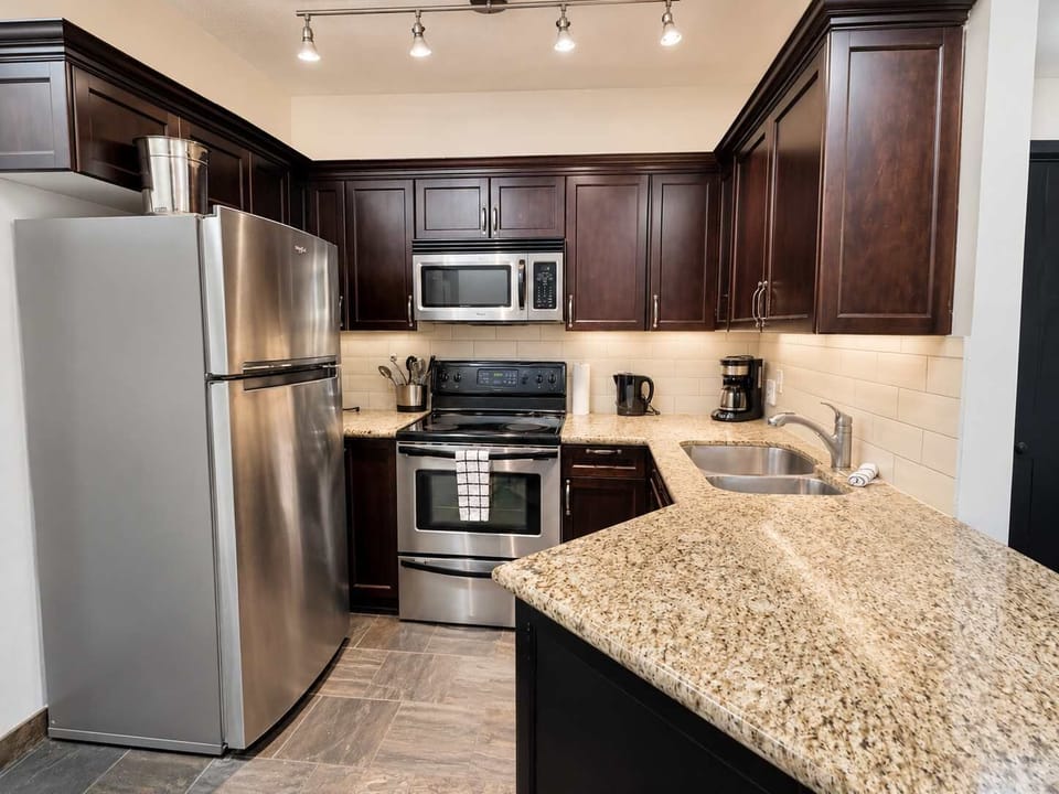 Well equipped kitchen with granite countertop and stainless steel appliances