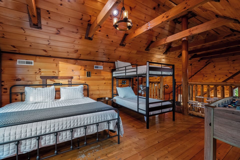 Loft bedroom with king bed, twin/twin bunk, TV, and foosball table. 