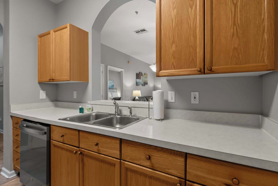 Kitchen with wooden cabinets and a double stainless steel sink overlooking the living area