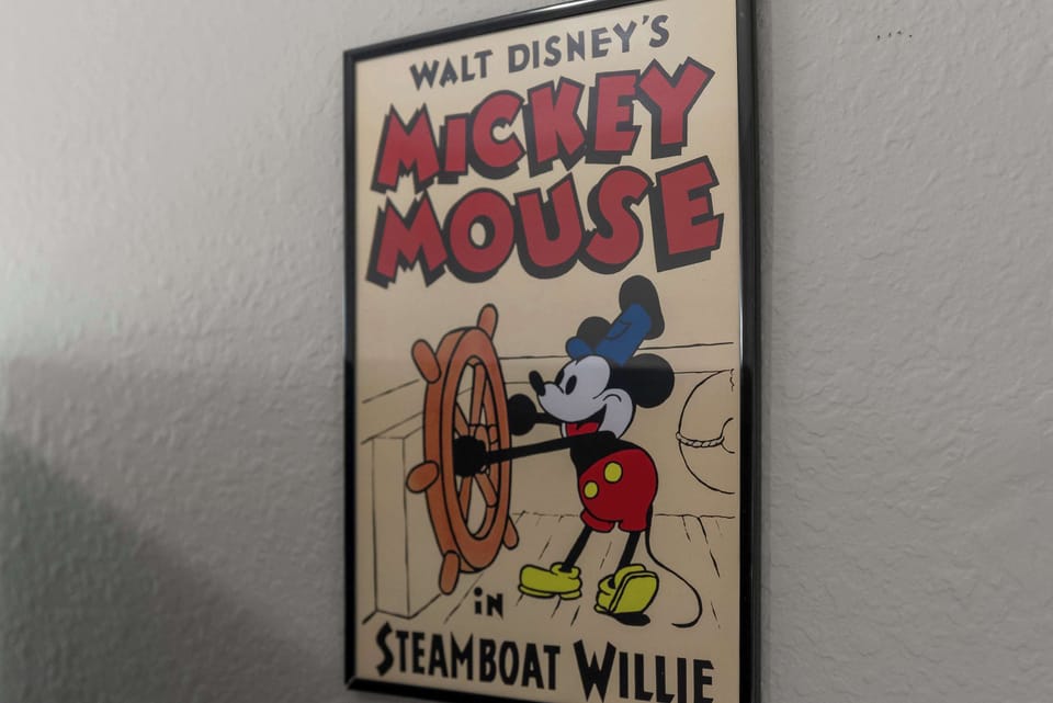 Framed vintage mickey mouse steamboat willie poster adds nostalgic charm to the room.