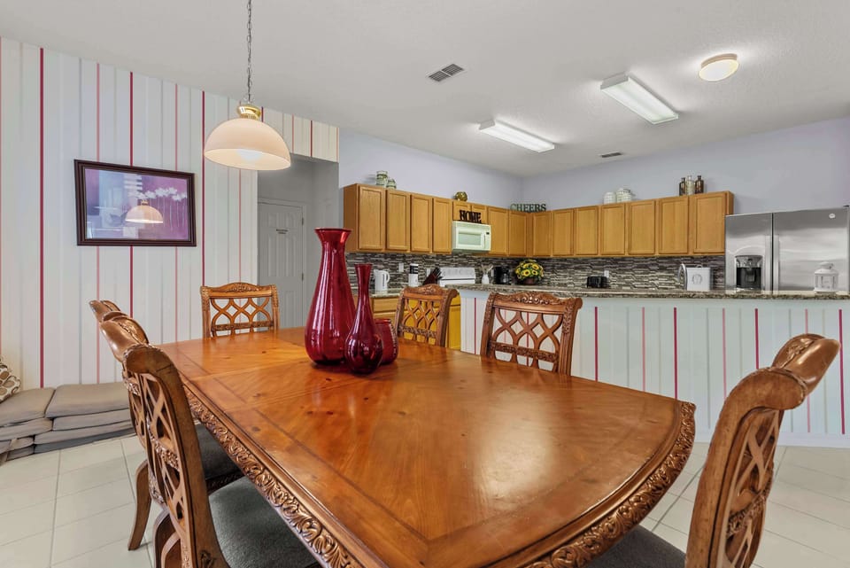 Dining area with carved wooden chairs and a kitchen featuring oak cabinets and a mosaic tile backsplash.
