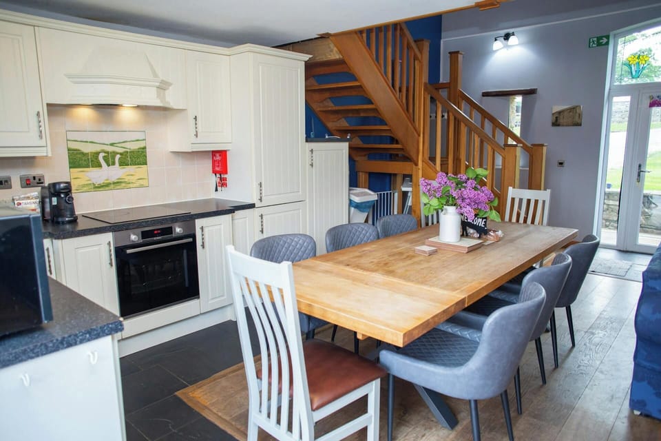 Open-plan kitchen dining area with wooden table, mixed chairs and staircase