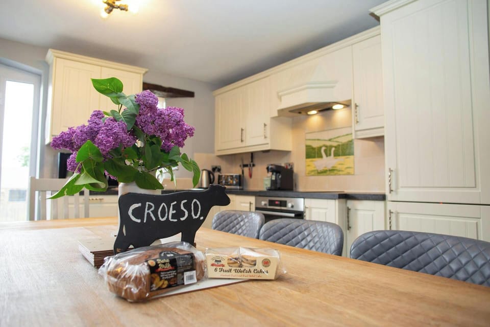 Dining table with croeso sign, loaf of bread and eggs in foreground, kitchen behind