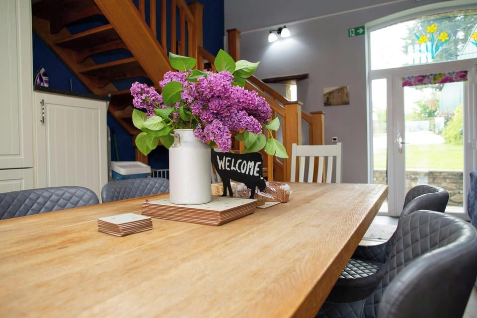Wooden dining table with vase of lilac flowers in a bright room