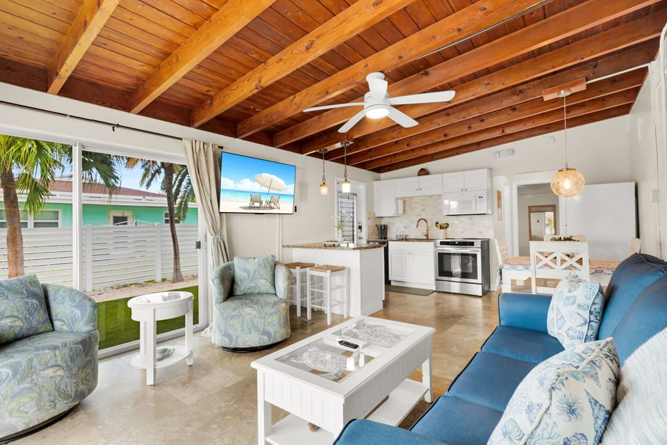 Relax in the bright living room featuring vaulted wood-beam ceilings, comfortable furnishings, and a welcoming coastal feel for your Key Colony Beach getaway.
