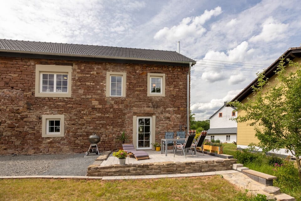 Der Außenbereich hinter dem Haus lädt zu entspannten Stunden im Freien ein – ideal für ein gemeinsames Essen, einen Grillabend oder einfach eine ruhige Pause mit Blick ins Grüne.